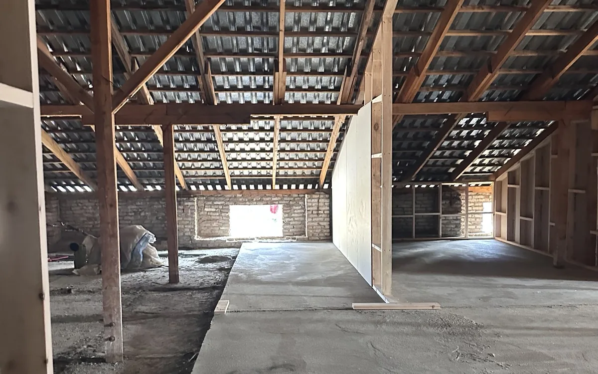 The floor part-framed: first stud walls up, brick end wall, concrete poured